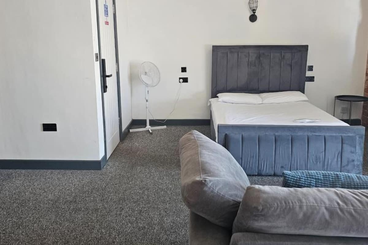 Un dormitorio con cama, mesita de noche, ventilador y lámpara colgante.