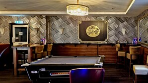 A billiards room with a pool table, chairs, a bar area, and a chandelier. - Sapphire Hotel Blackpool (Blackpool)