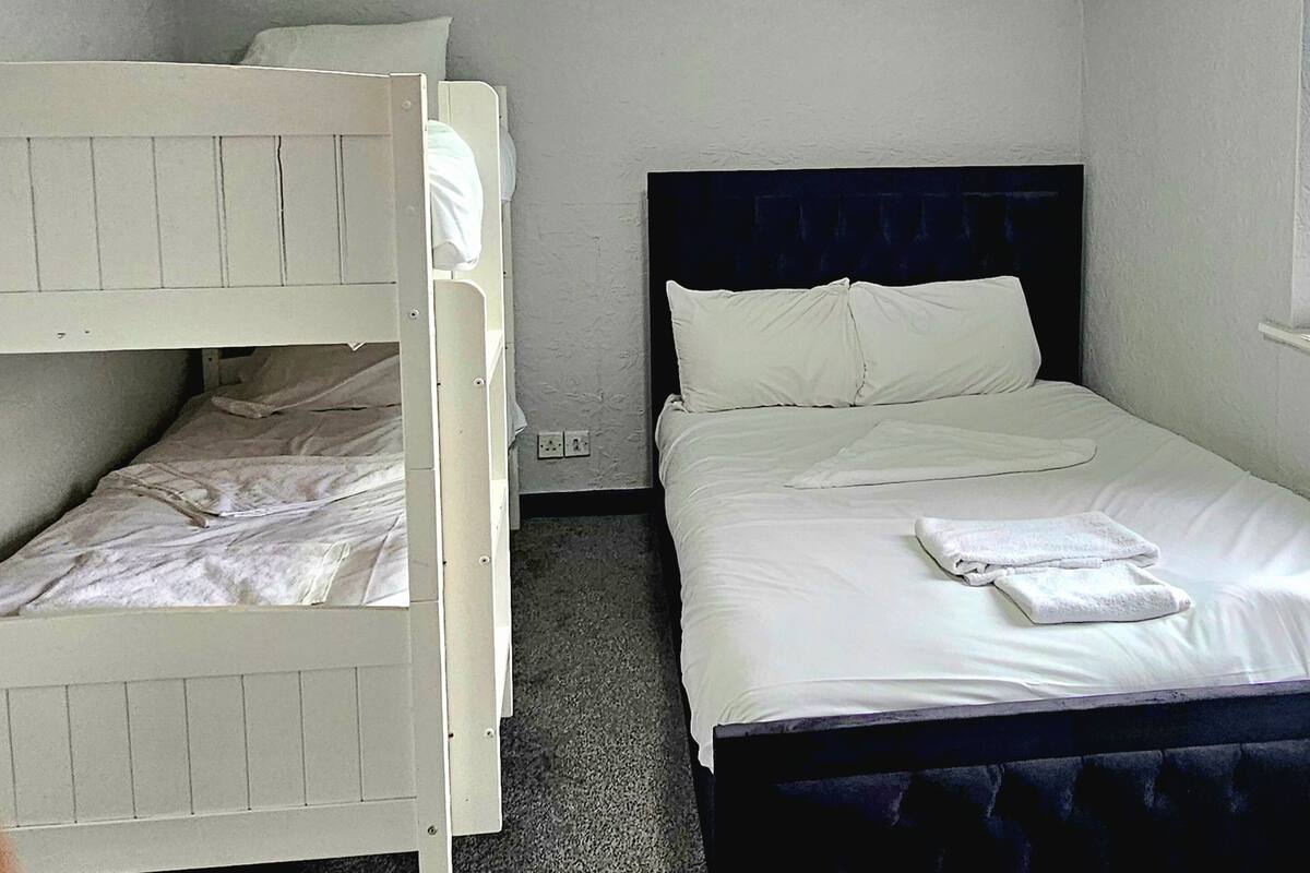 Una habitación con una cama litera, una cama individual y un cabecero que tiene la palabra 'HOME'.