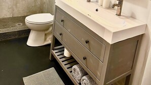 A modern bathroom with a shower, toilet, vanity, and a large mirror. - Modern Studio w/ Private Bath, Fast Wi-Fi, Laundry (Zephyrhills)