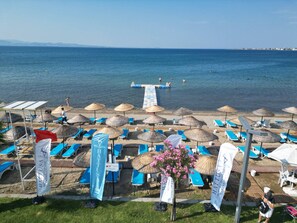 Una playa con sombrillas, sillas de descanso y una zona de piscina.