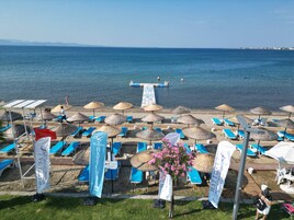 A beach with umbrellas, lounge chairs, and a pool area.