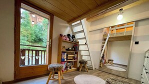 Una stanza accogliente con pavimento in legno, una libreria, una scala e un piccolo sgabello.