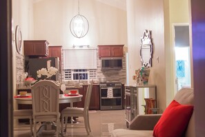 Cozinha moderna com área de refeições, com lustre, eletrodomésticos embutidos e vista para a sala de estar.