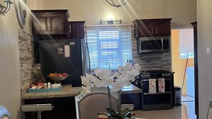 A modern kitchen with a dining area, featuring a stainless steel refrigerator, a microwave, and a built-in oven. - Royal Vacation Retreat (Falmouth)