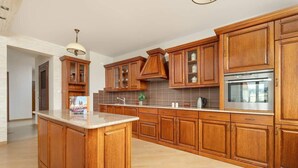 Eine geräumige Küche mit Holzausstattung, einer großen Kochinsel und einem eingebauten Backofen.