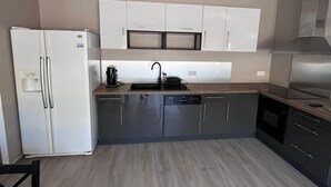 Una cocina moderna con horno integrado, pileta y refrigerador.