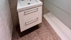 Un baño moderno con tocador blanco, un espejo grande con iluminación integrada y pared de azulejos.