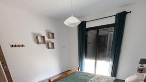 Un dormitorio con cama, mesita de noche de madera y lámpara colgante.