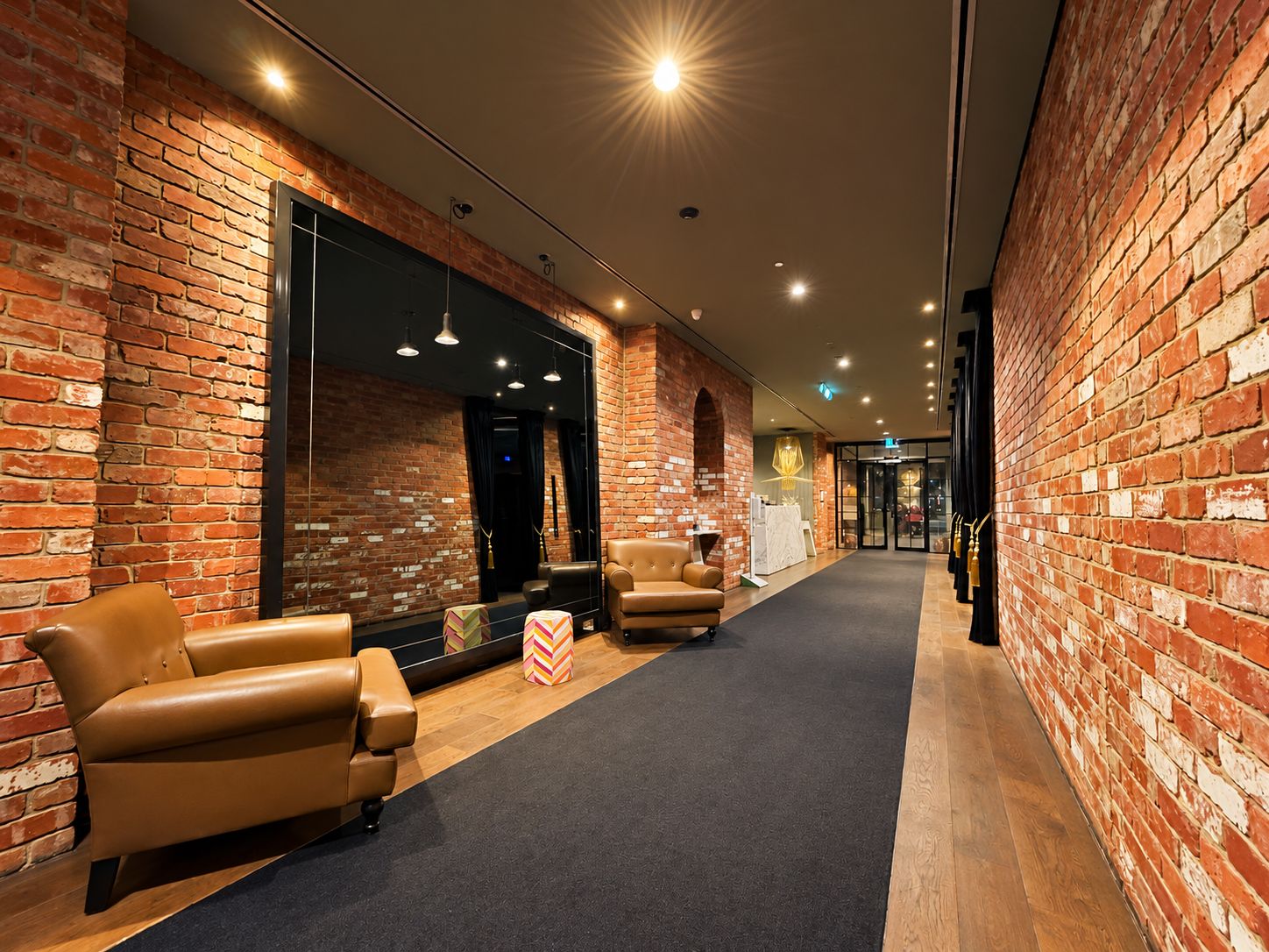 A hallway with brick walls, leather chairs, and a carpeted floor.