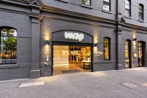 A building with a storefront labeled 'wrap' featuring a glass entrance and a brick facade.
