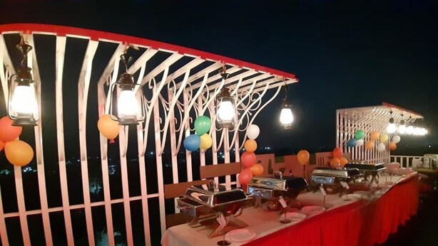 An outdoor event setup with a stage, tables, and lighting. - HOTEL KAMBAA JAWAI (Sumerpur)