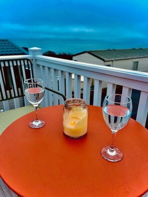 Une table avec deux verres de vin et une bougie sur un balcon.
