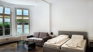 A modern hotel room with a sofa, a bed, and a glass coffee table. - Schöne, Frisch Sanierte Ferienwohnung, Ideal für Familien Aufenthalte (Hamburg)