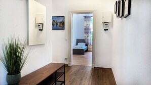A hallway with a wooden bench, a potted plant, and a bed visible through an open door. - Schöne, Frisch Sanierte Ferienwohnung, Ideal für Familien Aufenthalte (Hamburg)