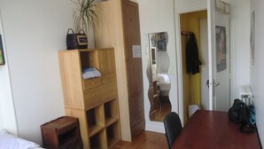 A compact room with a bed, a wooden wardrobe, a desk, and a mirror. - Quiet, bright apartment with private parking near central Paris (Paris)