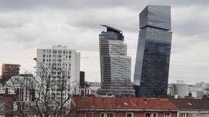 A cityscape with modern high-rise buildings, including a distinctive curved skyscraper and a tall rectangular building with reflective glass. - Quiet, bright apartment with private parking near central Paris (Paris)