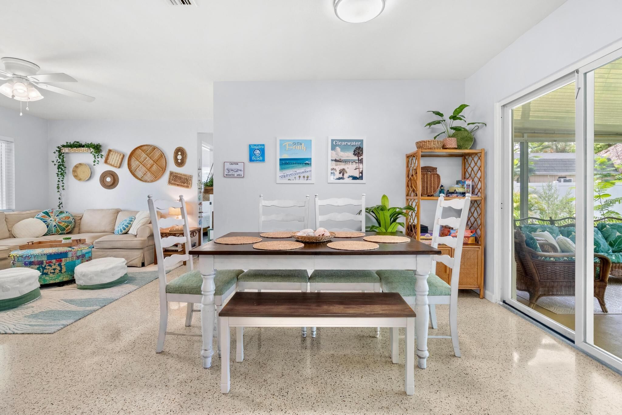 A dining area with a white table, green cushioned benches, and a ceiling fan.