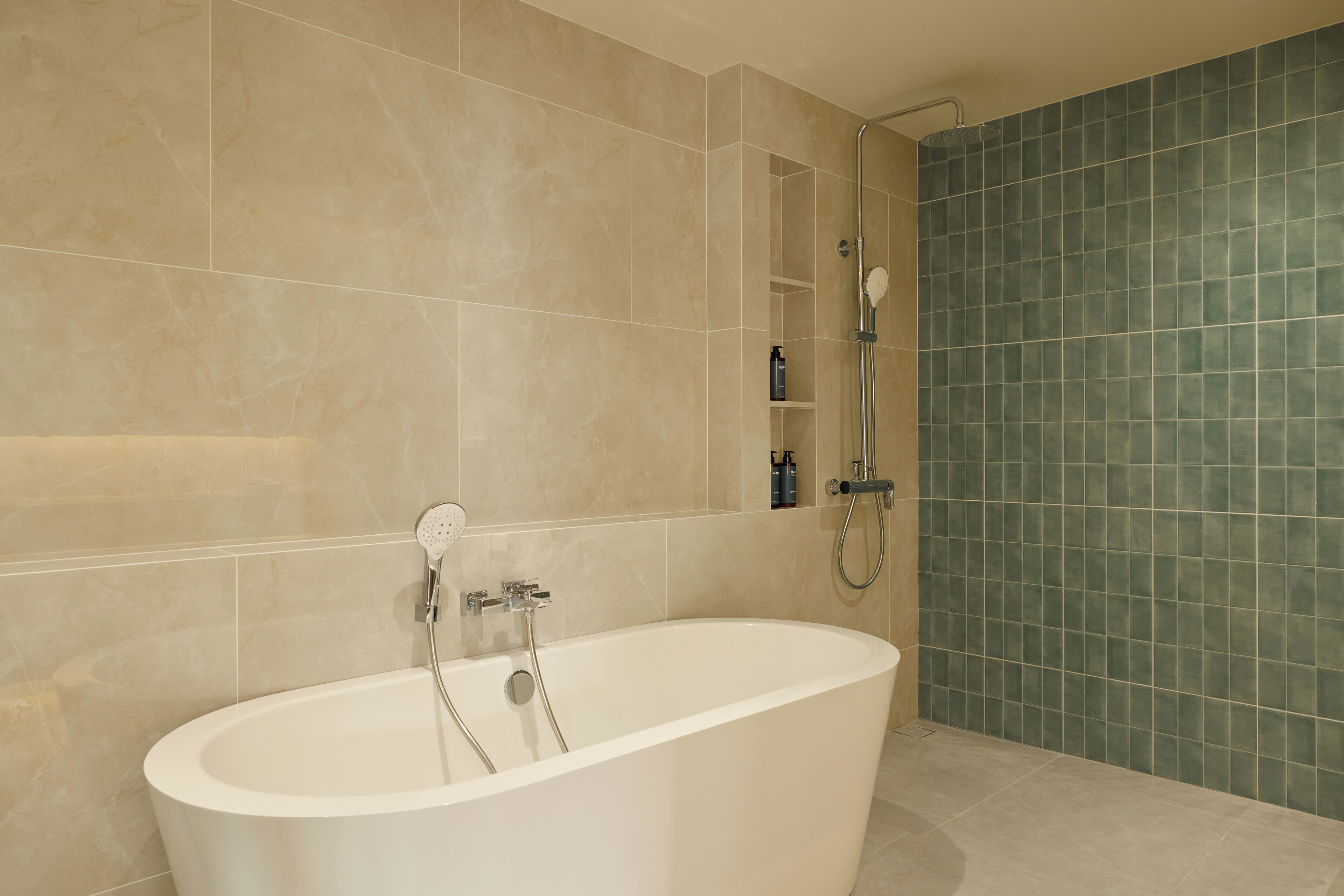 A modern bathroom with a freestanding bathtub, a shower area, and a tiled wall.