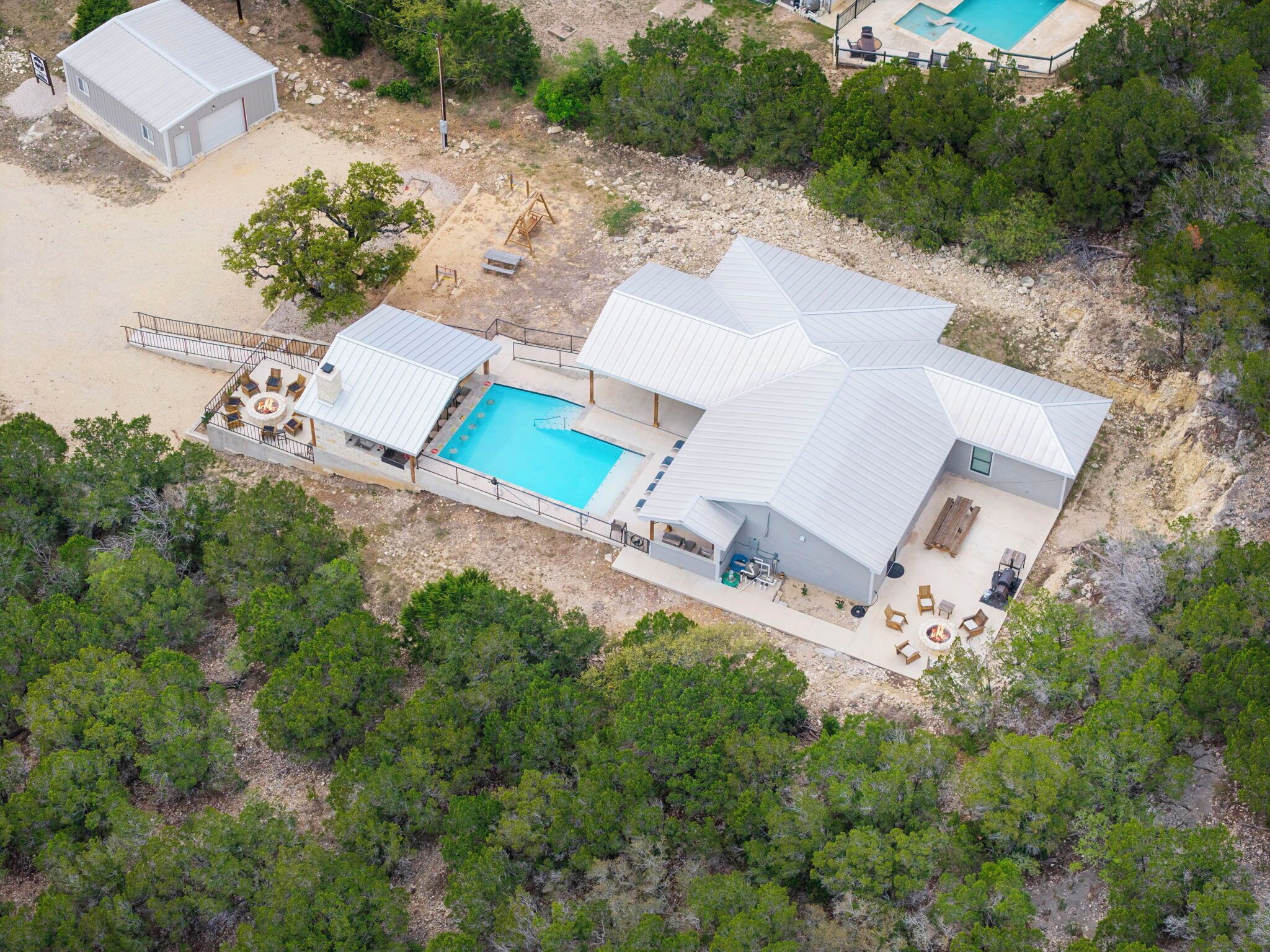 Vista aerea di un resort con una grande piscina, diverse camere per gli ospiti e aree salotto all'aperto.