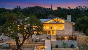 A stone building with a covered patio, outdoor seating, and a staircase leading to the entrance. - The Wolves Den @ Frio River Vacation Rentals (Concan)