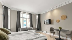 Une chambre d’hôtel avec un grand lit, une petite table, un téléviseur et une vue sur la ville.