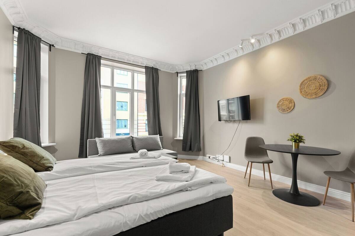 Une chambre d’hôtel avec un grand lit, une petite table, un téléviseur et une vue sur la ville.