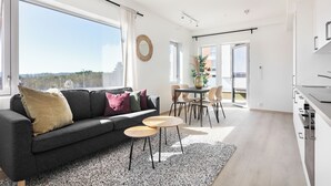 Un salon moderne avec un canapé gris, deux petites tables rondes et un coin repas comprenant une table et des chaises.