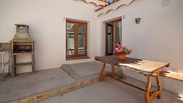 Un patio al aire libre con una mesa de madera, una planta en maceta y un horno de ladrillo.