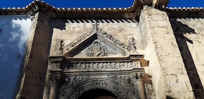 Une façade en pierre richement décorée de sculptures complexes et surmontée d’un toit en tuiles.