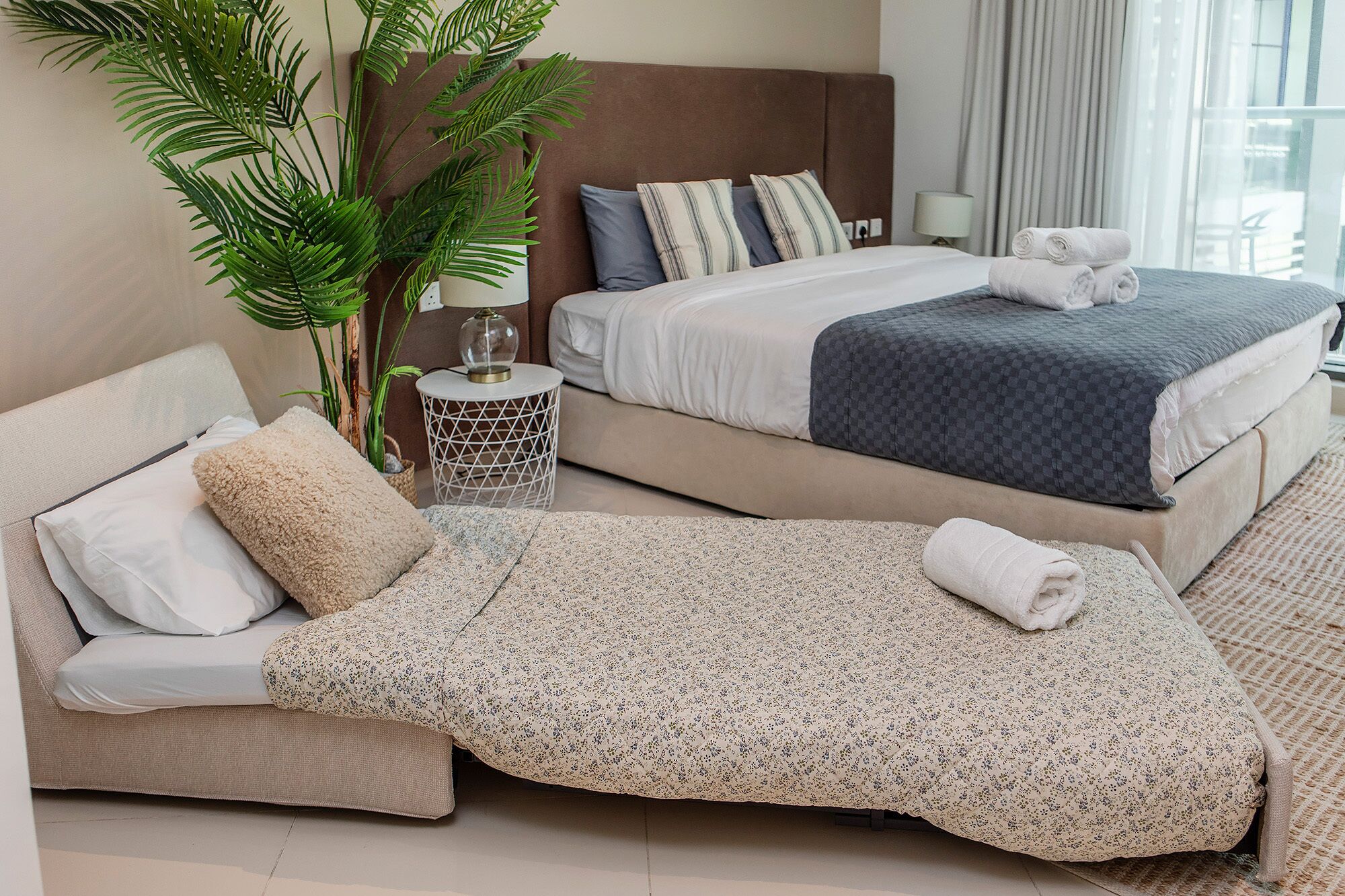 Ein Hotelzimmer mit einer Couch, einer Schlafgelegenheit, einem Bett, einer Topfpflanze und einer Lampe.