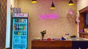 A reception area with a neon sign, a beverage dispenser, and a reception desk.