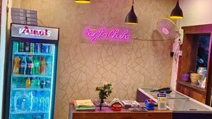 A reception area with a neon sign, a beverage dispenser, and a counter with various items.