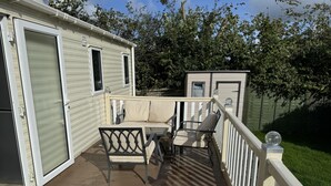 A covered deck with a sofa and chairs, a small table, and a white railing. - Caravanbreak/ 3bed/ Petsok/freep/ Tv/ Wifi (Launceston)