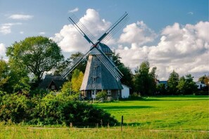 A traditional windmill with a house attached, surrounded by greenery and a clear sky. - Ferienhaus mit Sauna in Boiensdorf (Boiensdorf)