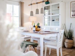 A dining area with a white table, chairs, a lamp, and a fruit bowl. - Ferienhaus mit Sauna in Boiensdorf (Boiensdorf)