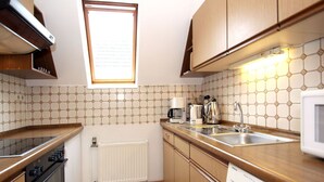 Eine kleine Küche mit Holzausstattung, einem Backofen, einer Mikrowelle, einer Kaffeemaschine und einem Geschirrspüler.