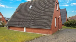 Ein eingeschossiges Backsteinhhaus mit steilem Dach, einem kleinen Fenster und einem sichtbaren Schornstein.