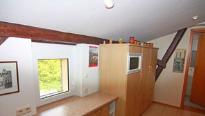 A kitchen with wooden cabinets, a window, and a microwave. - Behagliche Ferienwohnung im Idyllischen Korchow (Biendorf)