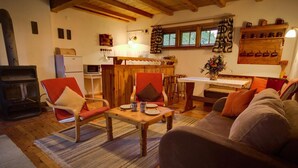 A cozy living room with a wooden table, two armchairs, a sofa, and a kitchen area in the background. - Apartment in Masuria With Private Pond (Gizycko)
