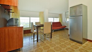 A compact room with a kitchenette, a dining area, and a sofa.