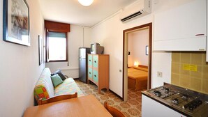 A compact kitchen with a stove, a refrigerator, and a dining area with a table and chairs.