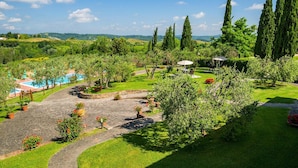 Un jardin aménagé avec une piscine, des allées pavées et de grands cyprès.
