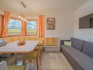 Un coin repas avec une table, des chaises et un saladier rempli de fruits.