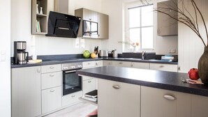 Une cuisine moderne avec des armoires blanches, un plan de travail noir et un four à micro-ondes encastré.