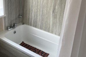 Een bad/douchecombinatie, een diep bad, handdoeken