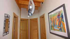 A hallway with wooden doors, a ceiling fan, and a framed abstract painting. - Ferienwohnung Strandanker in Monkebude (Monkebude)
