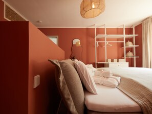 Une chambre moderne avec un lit, une étagère blanche et un luminaire suspendu.