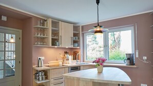 Eine moderne Küche mit Holzausstattung, einer integrierten Kücheninsel und einem großen Fenster für natürliches Licht.