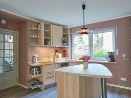 Eine moderne Küche mit Holzausstattung, einer integrierten Kücheninsel und einem großen Fenster für natürliches Licht.